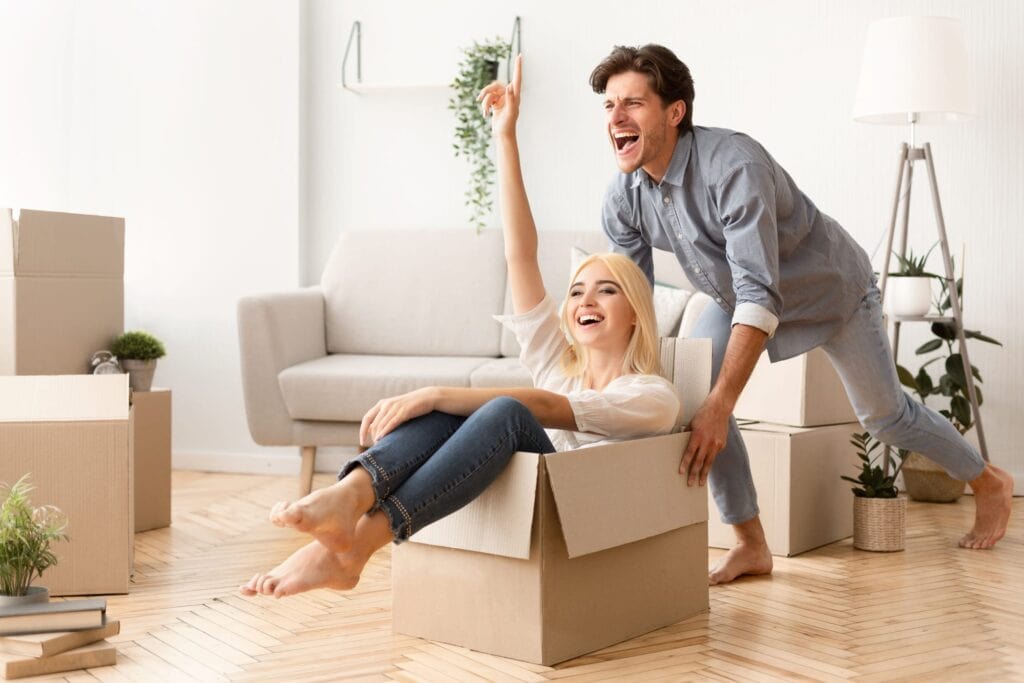 Moving New Home. Couple Having Fun Among Packed Cardboard Boxes.