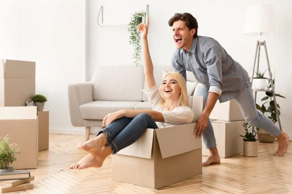 Moving New Home. Couple Having Fun Among Packed Cardboard Boxes. 